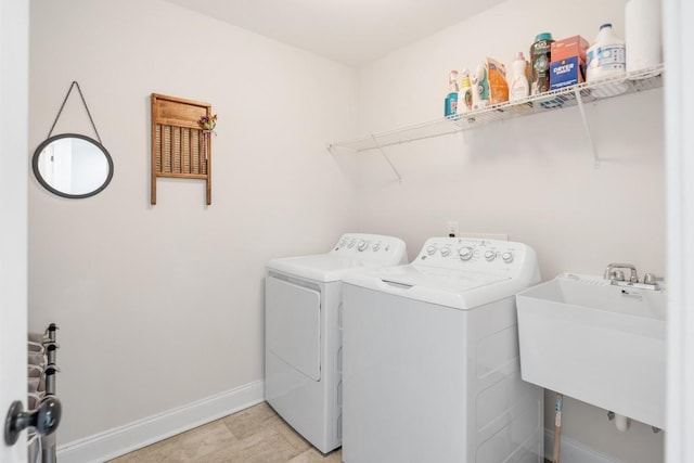 laundry area with a sink, laundry area, washing machine and clothes dryer, and baseboards