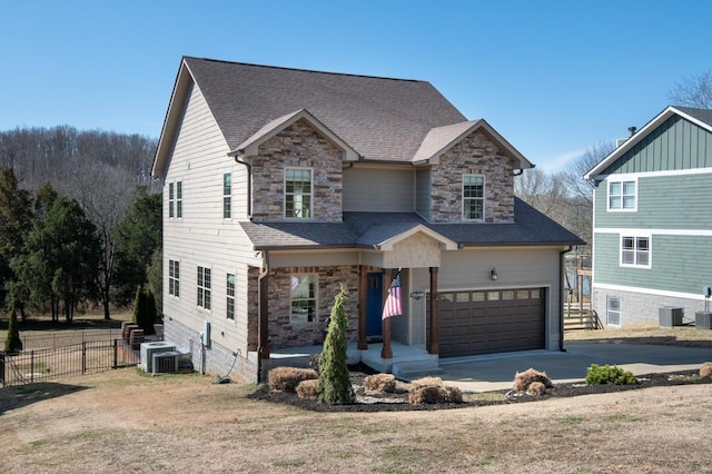 view of front of house with a garage, stone siding, fence, and central air condition unit