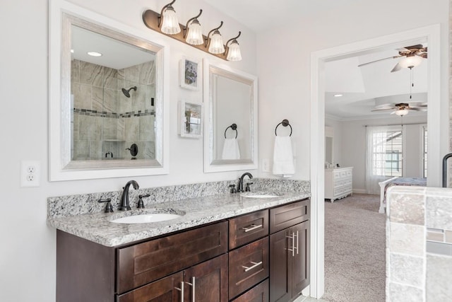 ensuite bathroom featuring double vanity, tiled shower, a sink, and crown molding