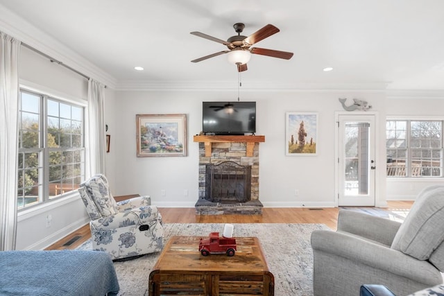 living room with a fireplace, crown molding, baseboards, and wood finished floors