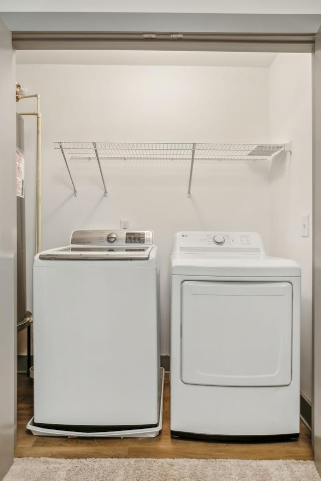 laundry area with laundry area, wood finished floors, and washing machine and dryer