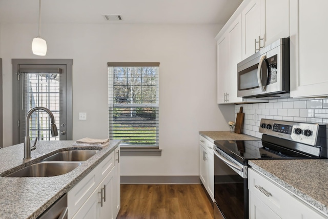 kitchen with stainless steel appliances, dark wood-style flooring, a sink, tasteful backsplash, and decorative light fixtures