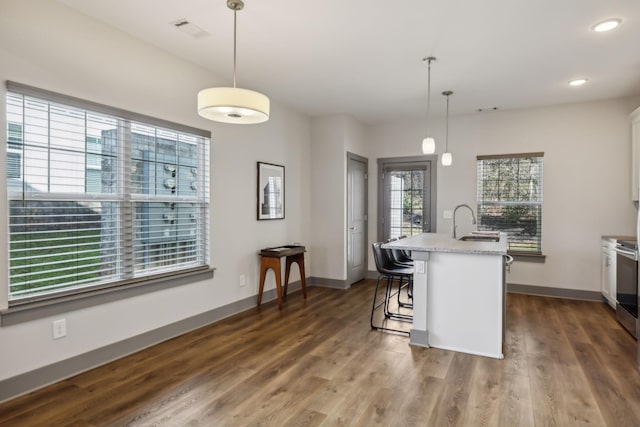 kitchen with baseboards, a kitchen island with sink, visible vents, and dark wood-style flooring