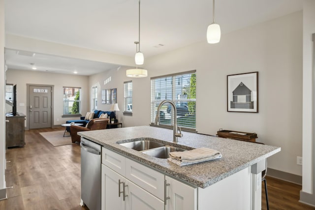 kitchen featuring wood finished floors, a sink, white cabinetry, stainless steel dishwasher, and pendant lighting