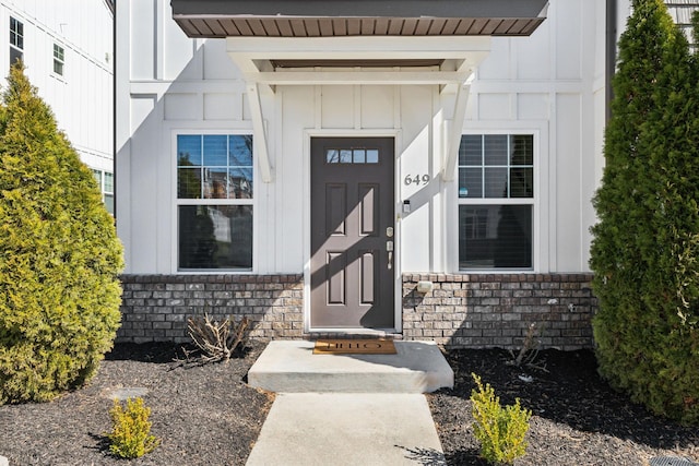 view of exterior entry with board and batten siding and stone siding