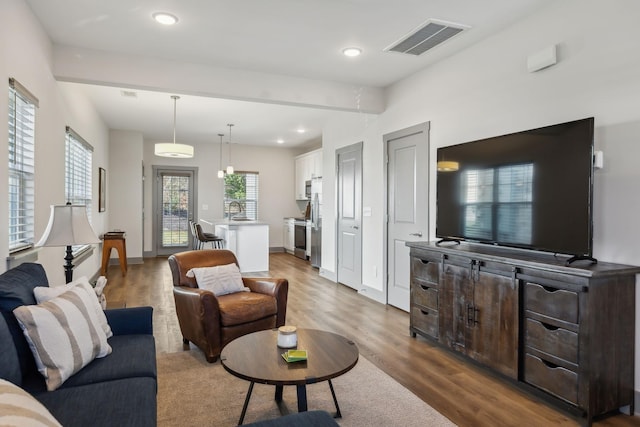 living room featuring recessed lighting, wood finished floors, visible vents, and baseboards