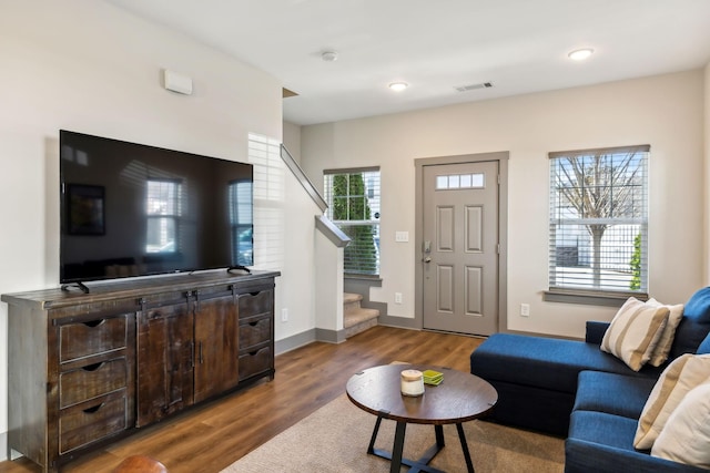 living room featuring stairs, wood finished floors, visible vents, and baseboards