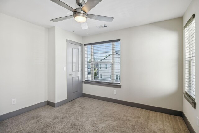 unfurnished room with carpet floors, a ceiling fan, visible vents, and baseboards