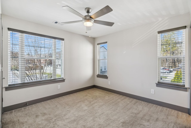 empty room with a wealth of natural light, visible vents, baseboards, and carpet flooring