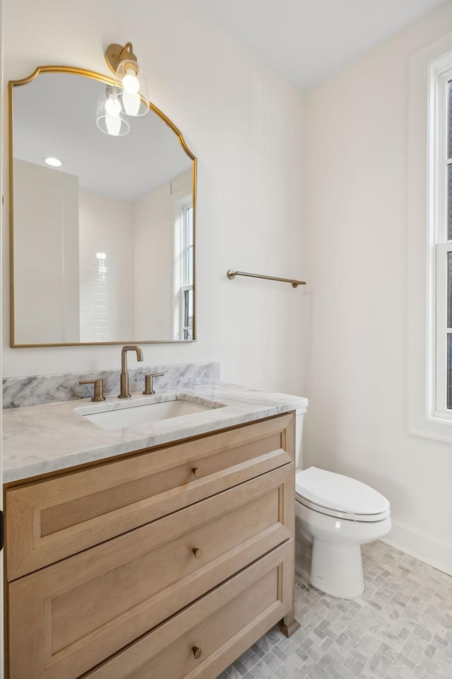 half bath featuring vanity, toilet, and baseboards