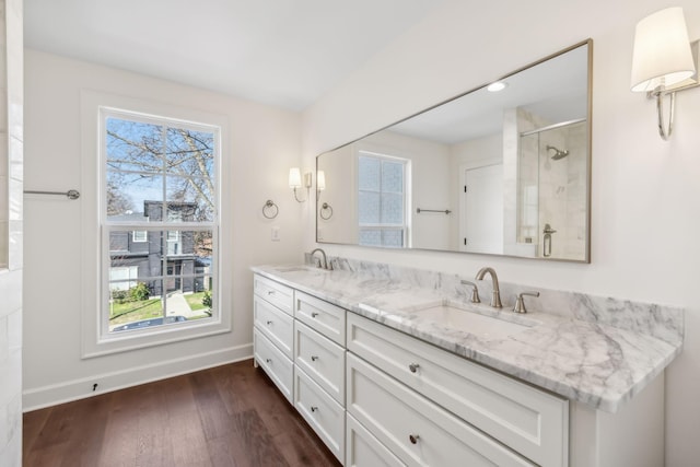 bathroom with double vanity, wood finished floors, a sink, and a shower stall