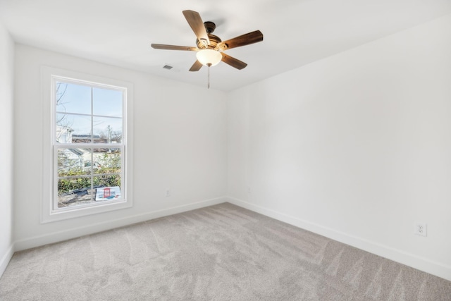 carpeted empty room with baseboards, visible vents, and a ceiling fan