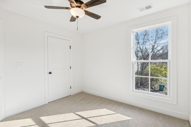 unfurnished room with baseboards, a ceiling fan, visible vents, and light colored carpet