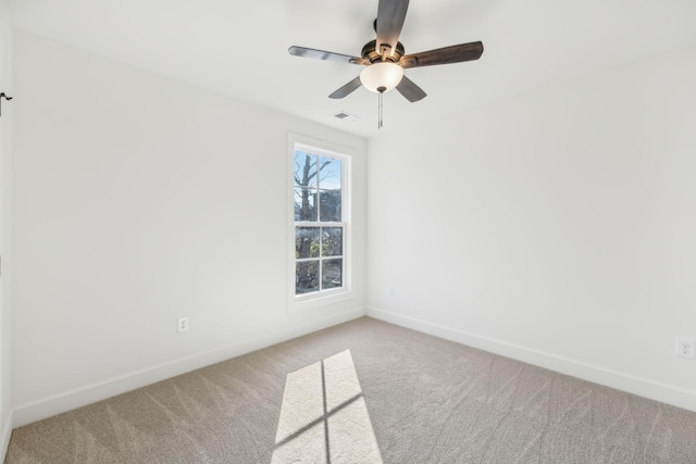 empty room featuring carpet flooring, ceiling fan, visible vents, and baseboards