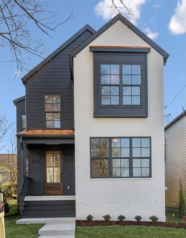 view of front facade with a front lawn, a porch, and brick siding