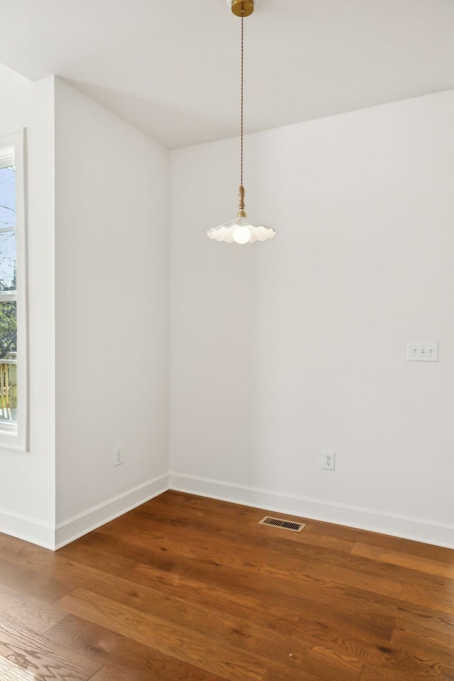 unfurnished dining area with wood finished floors, visible vents, and baseboards