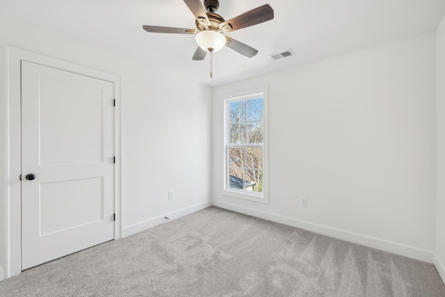 unfurnished room with carpet floors, ceiling fan, visible vents, and baseboards