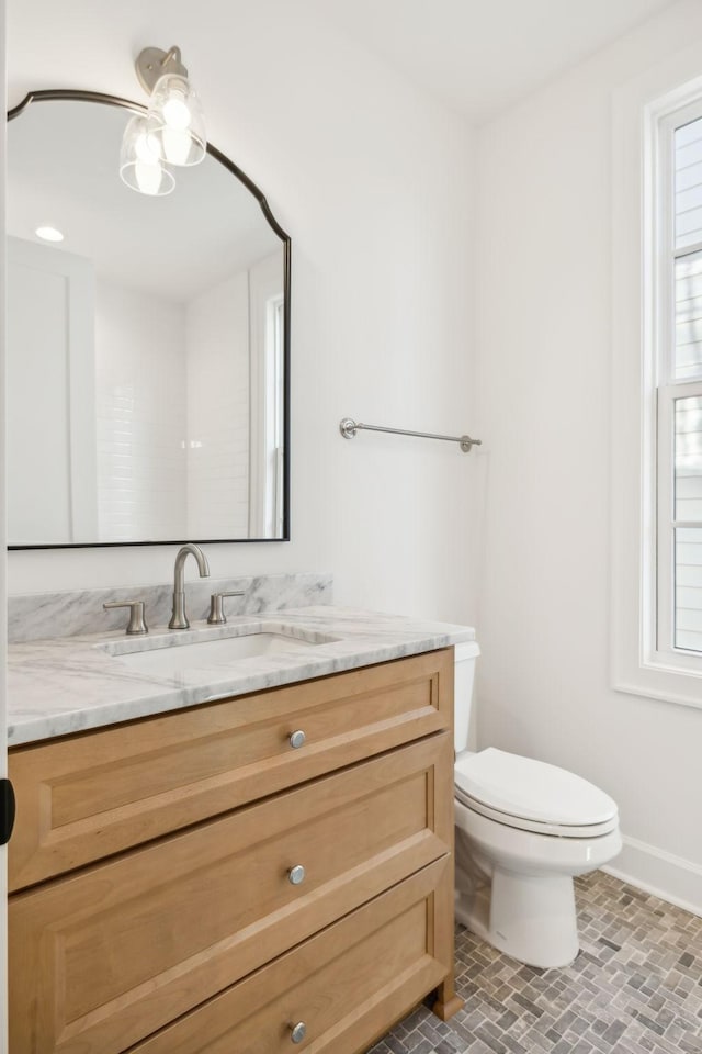 bathroom with toilet, brick floor, baseboards, and vanity