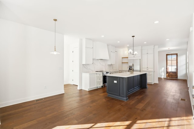 kitchen with dark wood-style flooring, stainless steel appliances, tasteful backsplash, light countertops, and custom range hood