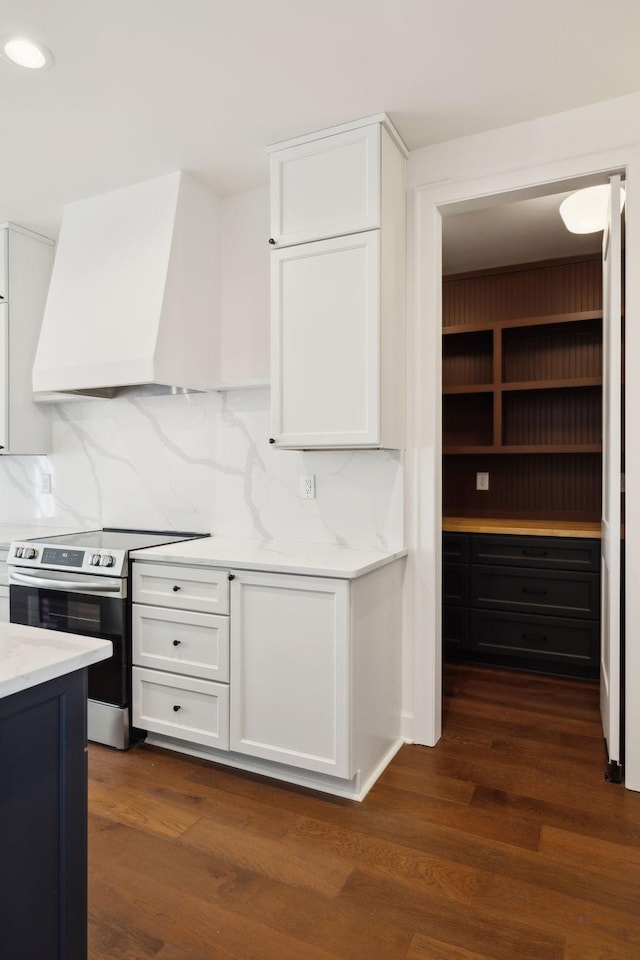 kitchen with stainless steel electric stove, dark wood-style flooring, white cabinetry, and custom range hood