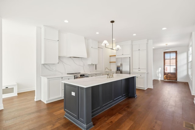 kitchen featuring visible vents, white cabinets, appliances with stainless steel finishes, premium range hood, and a sink