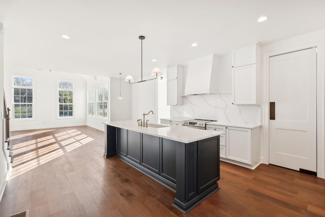 kitchen featuring decorative backsplash, dark wood finished floors, custom range hood, light countertops, and stainless steel range with electric cooktop