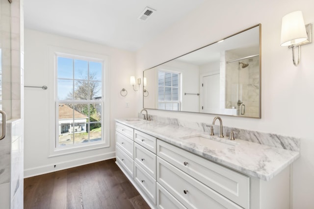 full bath with wood finished floors, a sink, visible vents, and a shower stall