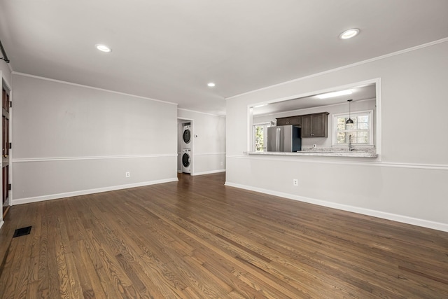 unfurnished living room featuring ornamental molding, dark wood-type flooring, and stacked washer / drying machine