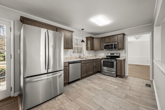 kitchen with stainless steel appliances, a healthy amount of sunlight, crown molding, and dark brown cabinetry