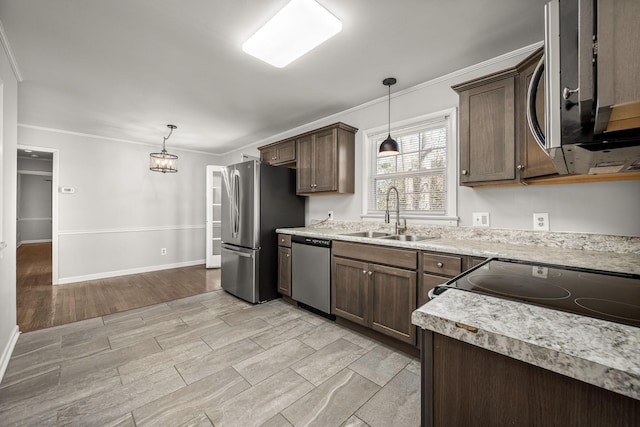 kitchen with crown molding, a sink, light countertops, appliances with stainless steel finishes, and pendant lighting