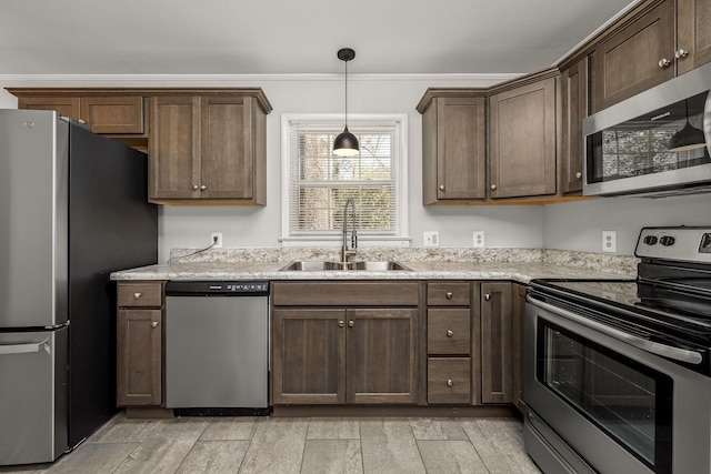 kitchen featuring stainless steel appliances, a sink, dark brown cabinetry, and decorative light fixtures