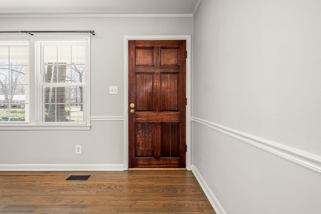 foyer entrance with ornamental molding, visible vents, dark wood finished floors, and baseboards