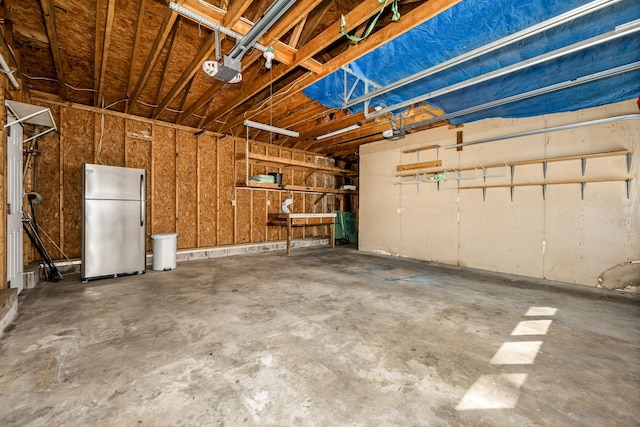 garage with a garage door opener and freestanding refrigerator