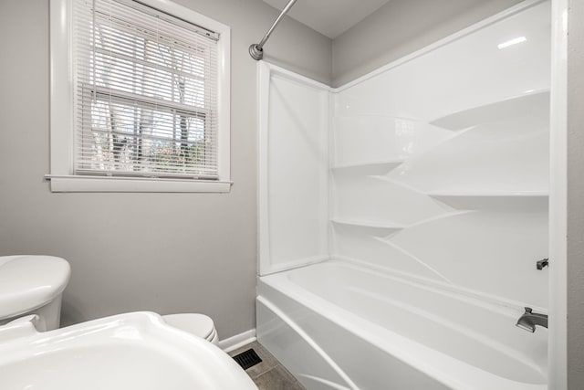 full bath with shower / bath combination, tile patterned flooring, toilet, and baseboards