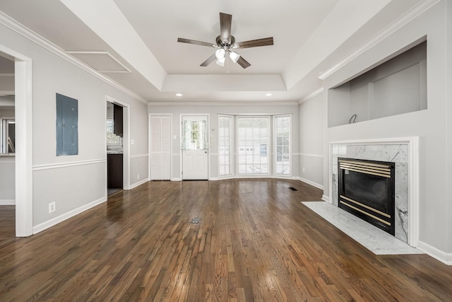 unfurnished living room with dark wood-type flooring, a premium fireplace, baseboards, electric panel, and a raised ceiling