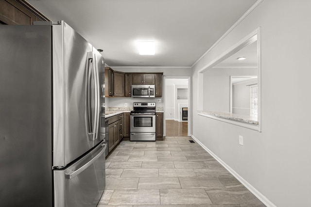 kitchen featuring baseboards, dark brown cabinets, appliances with stainless steel finishes, light countertops, and crown molding