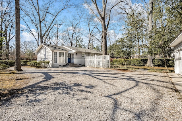 view of front of property featuring driveway and fence