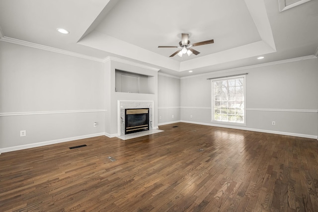 unfurnished living room featuring dark wood-style floors, a raised ceiling, visible vents, and a premium fireplace