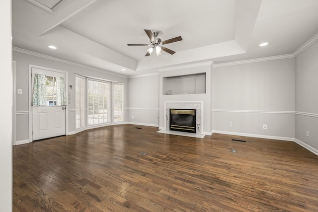 unfurnished living room featuring a raised ceiling, ceiling fan, a premium fireplace, and wood finished floors