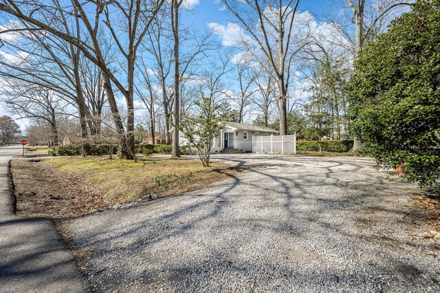 view of front facade with gravel driveway and fence