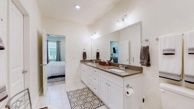 ensuite bathroom with toilet, connected bathroom, a sink, and double vanity