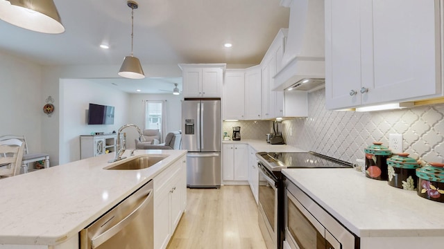 kitchen featuring light wood-style flooring, stainless steel appliances, a sink, custom exhaust hood, and backsplash