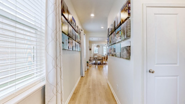 corridor with light wood finished floors, baseboards, and recessed lighting