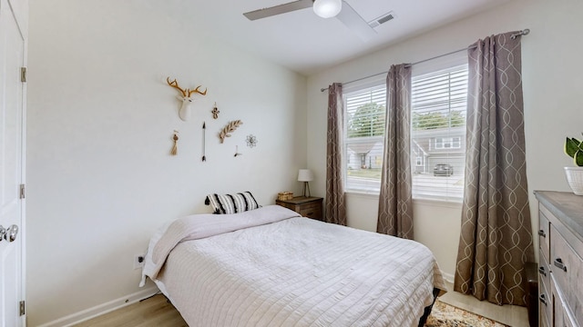 bedroom with ceiling fan, light wood finished floors, visible vents, and baseboards