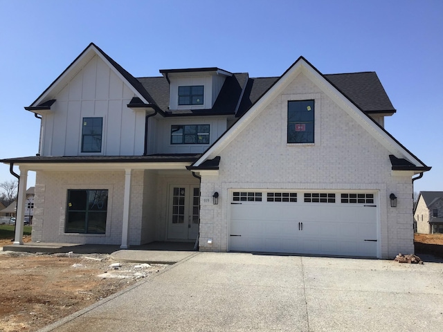 view of front of home with brick siding, board and batten siding, concrete driveway, and a garage