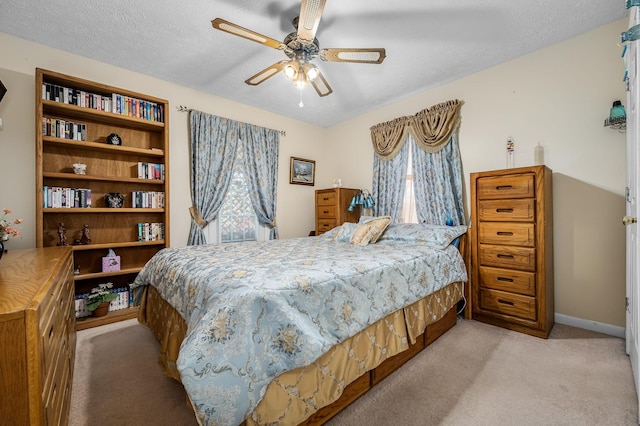 bedroom with a ceiling fan, light carpet, a textured ceiling, and baseboards