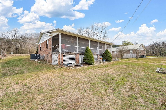 view of side of property featuring a yard, a sunroom, and central air condition unit