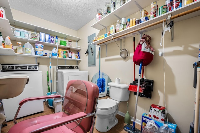 clothes washing area featuring a textured ceiling, laundry area, washer and clothes dryer, and baseboards