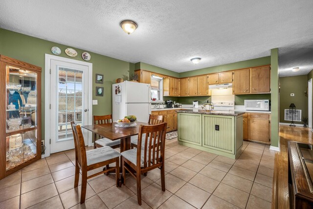 kitchen with light tile patterned floors, white appliances, a healthy amount of sunlight, and under cabinet range hood