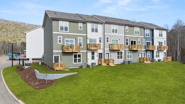 rear view of house with a residential view, a lawn, and central AC unit